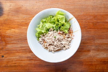 Thai Spicy Minced Pork with Egg Noodles served on a rustic wooden table.