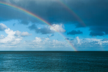 A vivid double rainbow spanning over the English Sea with clouds blue sky above.  Copy space available