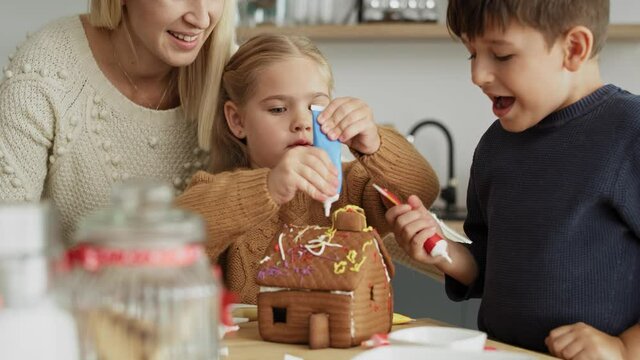 Video of cheerful children decorating homemade gingerbread house. Shot with RED helium camera in 8K.