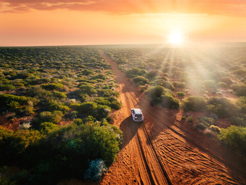 Australia, red sand unpaved road and 4x4 at sunset, freedom outback