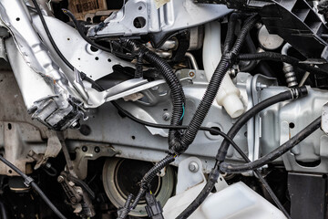 Obraz premium Close up shot of the remains of a wrecked vehicle after a serious car crash. Aftermath of drinking under influence, bent metal parts, smashed structure, ripped wires. Transport insurance concept.