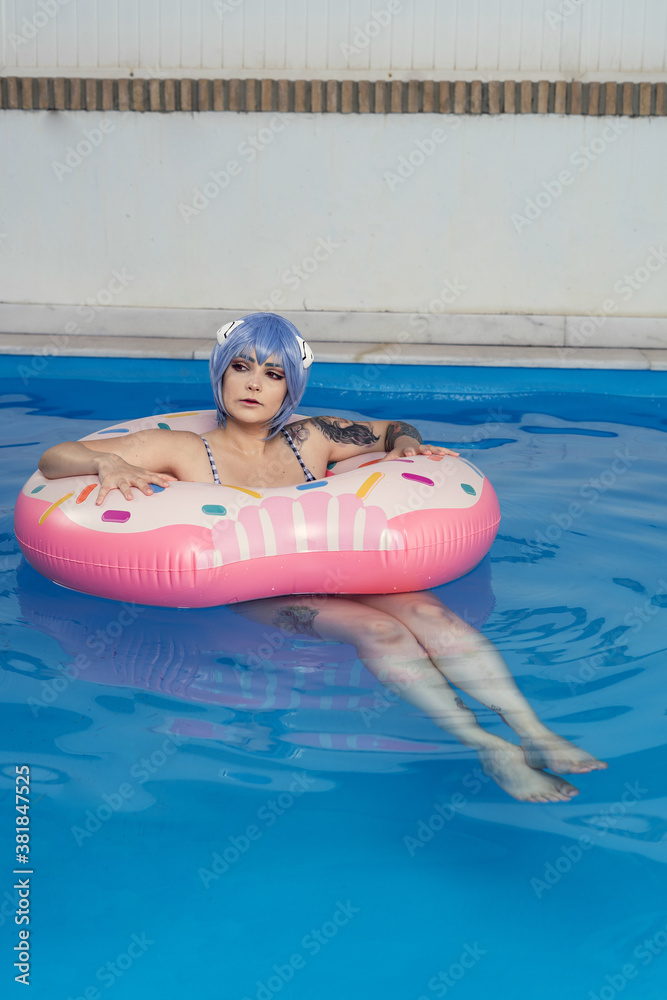 Sticker vertical shot of a european female with blue hair on an inflatable in a pool