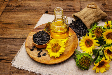 Sunflower oil in glass cruet with flower head and seeds in wooden bowl