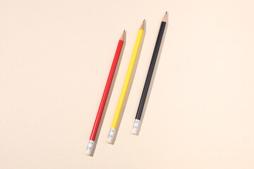 three different colors pencils on a beige paper background with copy space for your text