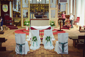 Church sanctuary before a wedding ceremony. Empty chairs for bride and groom.