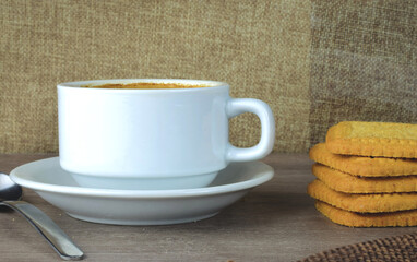 Breakfast first thing in the morning, white porcelain cup with coffee with milk, accompanied by baked cookies