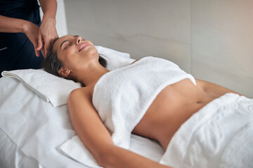 Fototapeta na wymiar Masseur hands massaging female head in spa salon