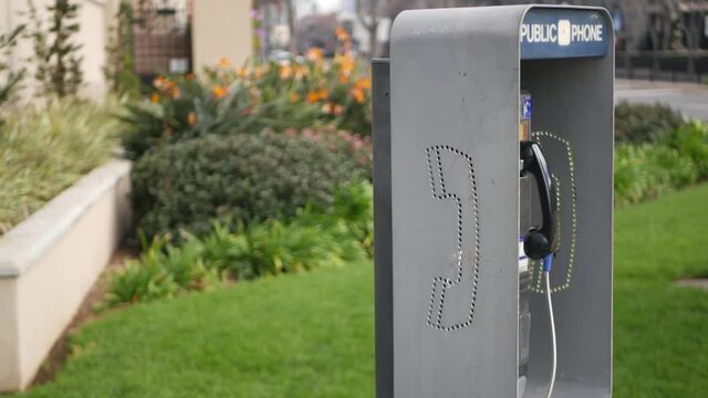 Retro coin-operated payphone station for emergency call on street, California USA. Public analog pay phone booth. Outdated technology for connection and telecommunication service. Cell handset on box.