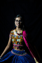Indian girl in traditional chaniya choli for navratri with a fashionable hairstyle poses in studio...