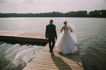 Bride and groom at a photo session in the nature. Lake and pier