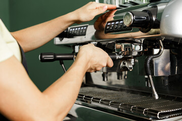 Woman coffee shop worker preparing coffee on professional coffee machine