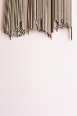 Soba Japanese spaghetti noodles on a light pink background with copy space. Food background concept