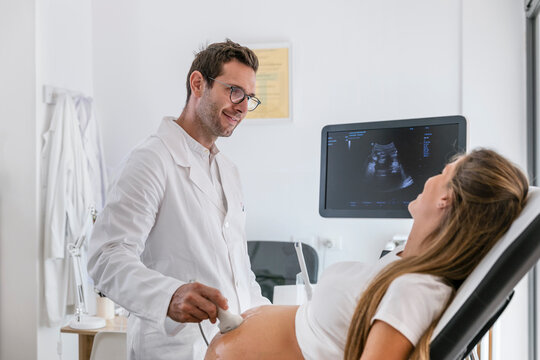 Friendly doctor talking with pregnant patient during sonography