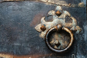 Steel black door of an ancient castle with a round vintage handle.