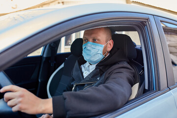 Fototapeta na wymiar Man with protective mask adriving a car by Coronavirus pandemic quarantine