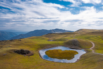 Beautiful mountain lake in O shape with cloudy sky background. Opera lake on wat to Burkhan bulak waterfall in Kazakhstan. Outdoor landscape. Tourism, journey in Kazakhstan concept.