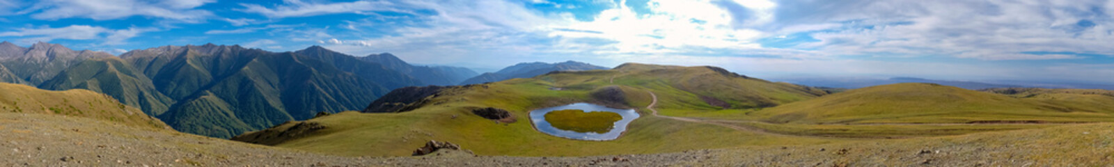 Beautiful mountain lake in O shape with cloudy sky background. Opera lake on wat to Burkhan bulak waterfall in Kazakhstan. Outdoor landscape. Tourism, journey in Kazakhstan concept.