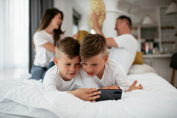 Two little brothers are playing games on the phone. Beautiful boys enjoying at home..