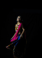 Indian girl in traditional chaniya choli for navratri with a fashionable hairstyle poses in studio...
