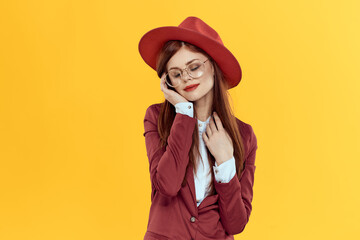 woman in red hat jacket glasses yellow background cosmetics