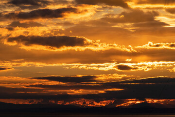 Fototapeta premium a golden image of the sun setting behind mountains and clouds in southern Spain 