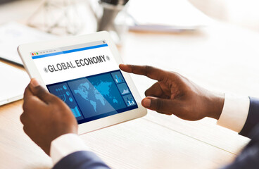 African Businessman Using Tablet Working With Economic Graphs In Office