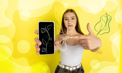 Pointing at the phone. Caucasian woman's portrait. Pretty female model in casual. Concept of human...