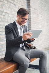 Smiling businessman listening music on tablet