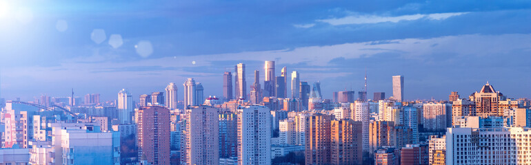 Blue tinted panorama of Moscow from aerial view. Cityscape with Moscow City in the distance and modern multi-storey residential buildings in the foreground