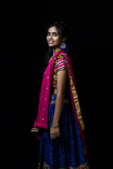 Indian girl in traditional chaniya choli for navratri with a fashionable hairstyle poses in studio...