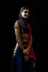 Indian girl in traditional chaniya choli for navratri with a fashionable hairstyle poses in studio...