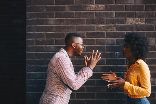 Young beautiful curly woman stands together with her man, she argues something while he listens and claims the opposite