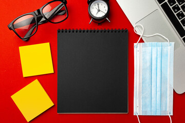 Black notepad page with stationery and medical mask top view