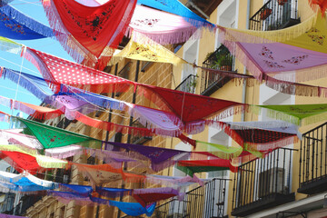 Classical Spanish shawls strung between the balconies outside on the street in La Latina district. Decorated ambient creates a festive mood. Madrid, Spain