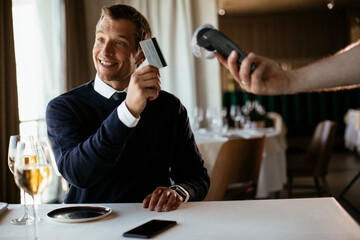 Businessman paying the bill with a credit card in restaurant.