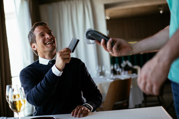 Businessman paying the bill with a credit card in restaurant.