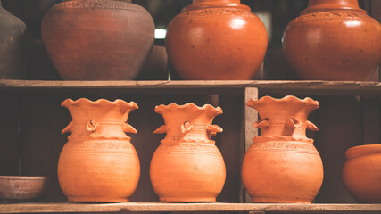 Fototapeta na wymiar Row of clay pottery on wooden shelf in vintage tone style