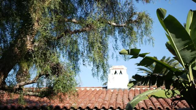 Mexican colonial style suburban, hispanic house exterior, green lush garden, San Diego, California USA. Mediterranean terracotta ceramic clay tile on roof. Rustic spanish tiled rooftop. Rural details.
