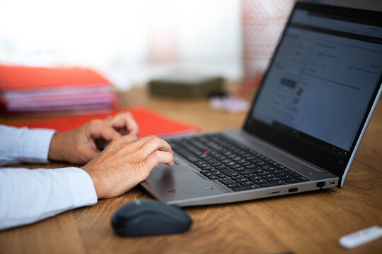Femme assise au bureau et qui tape sur son ordinateur portable ouvert, mains de femme