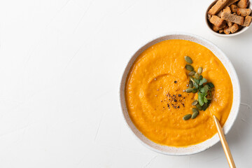 Fall pumpkin soup with crackers on white background. Top view. Space for text.