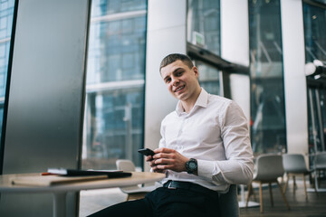 Glad male freelancer using smartphone in cafe during work