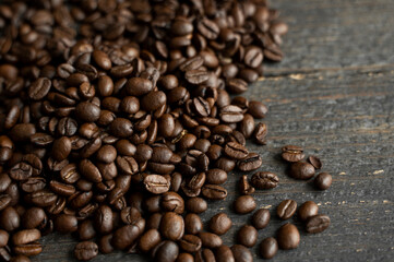 Roasted arabica coffee beans scattered on a wooden table. Fresh coffee beans.