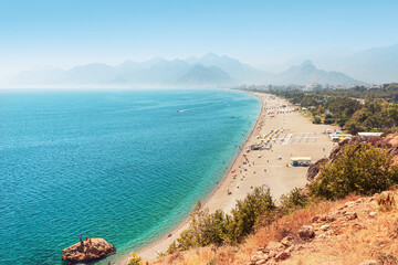 Naklejka premium famous long Konyaalti beach in Antalya. Turkish resort and Riviera with the Taurus mountains in the background.