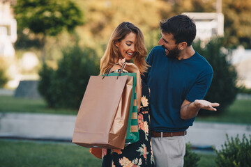 Naklejka premium Young attractive couple in love standing outdoors after shopping and hugging.