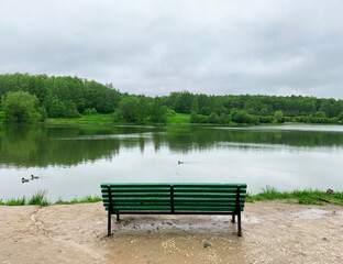 Obraz premium Bench on the Bank of the Lebedyansky pond, where ducks swim, in Izmailovsky Park, Moscow