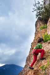 The child is climbing on a natural terrain.