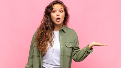  looking surprised and shocked, with jaw dropped holding an object with an open hand on the side