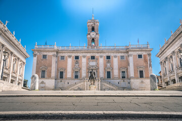 Obraz premium View of the of Campidoglio palace, seat of the city hall of Rome. Equestrian statue in the middle of the square. Municipal palace with the tower of clock in center. Postcard from the italian capital