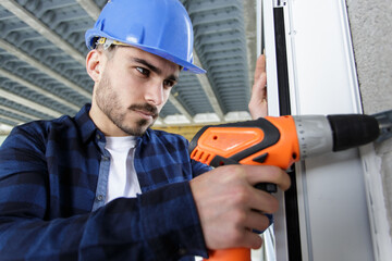 man with hard hat on construction site using drill