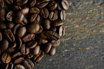 Roasted arabica coffee beans scattered on a wooden table. Fresh coffee beans.